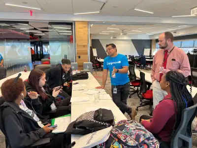 teens sit at a table with papers while adults instruct